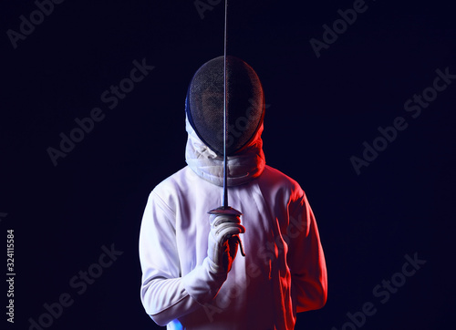 Toned photo of young fencer on dark background