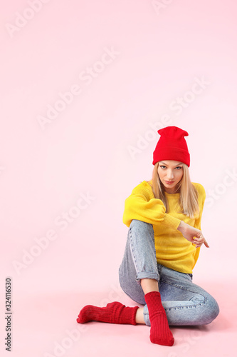 Young woman in warm sweater on color background © Pixel-Shot