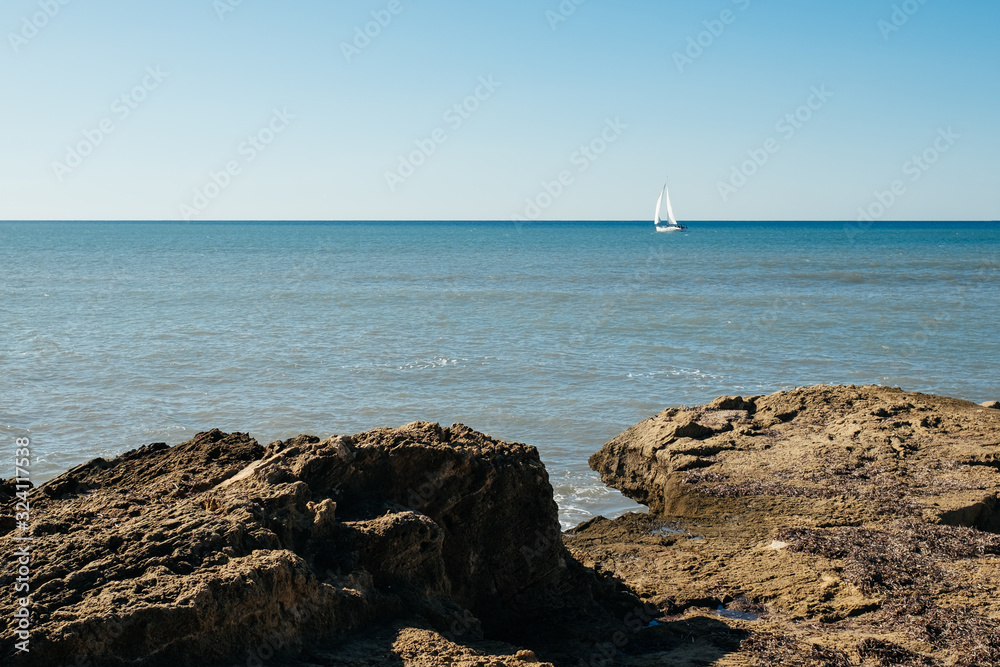 The view of Mediterranean sea, small yacht, and rocks The view of Mediterranean sea, small yacht, and rocks