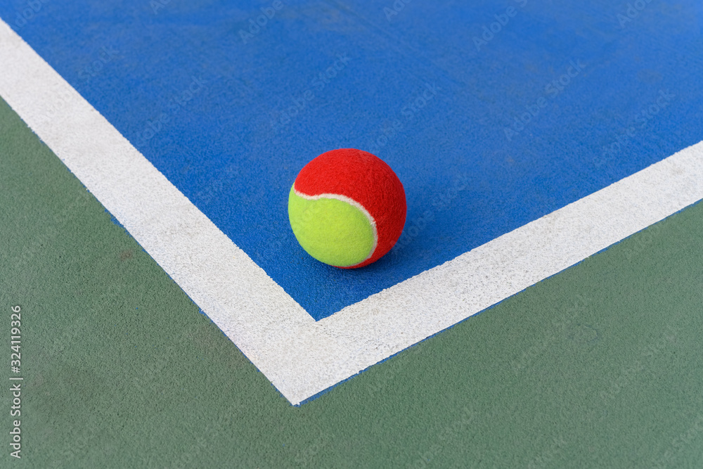 tennis ball on the floor of a blue court near the corner