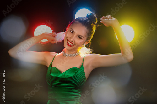 Portrait of Asian Woman Transgender wear Beautiful Green Evening long Gown, smile to camera over Back Lights colorful yellow, red, blur with smoke and poses fashion look, studio lighting copy space