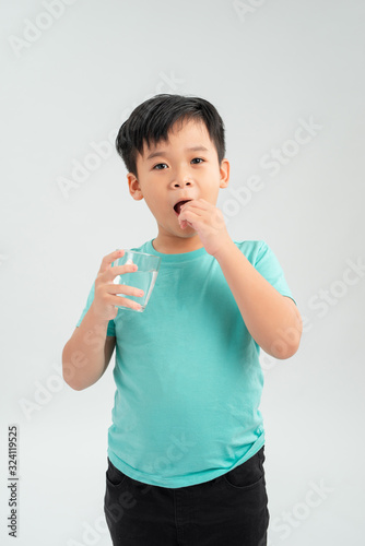 Young little Asian boy taking tablet medicine with a glass of water. Healthcare and Medical concept.