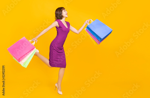  happy young womanl holding shopping bags and running