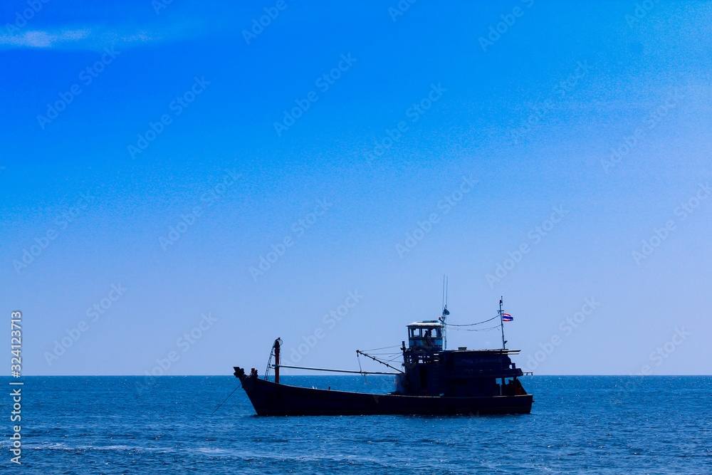 Obraz premium A fishing boat floats on Ko Lipe, Thailand on a day with clear blue sea and beautiful sunny skies.