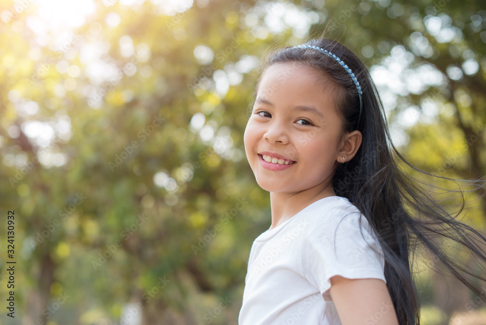 photo happy little asian girl child standing with big smile..fresh healthy green bio background with abstract blurred foliage and bright summer sunlight. concept of happy family or successful adoption photo happy little asian girl child standing with big smile..fresh healthy green bio background with abstract blurred foliage and bright summer sunlight. concept of happy family or successful adoption