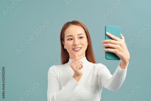 Fototapeta Selfie time. Joyful young women making selfie by her smart phone