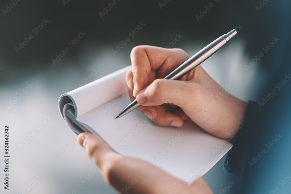 Woman hand holding notebook and pen at outdoor park. Woman hand holding notebook and pen at outdoor park.