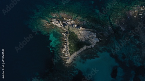 Aerial top down view of small island, islet in turquoise water of Aegean sea. Vourvourou beach, Halkidiki, Greece.