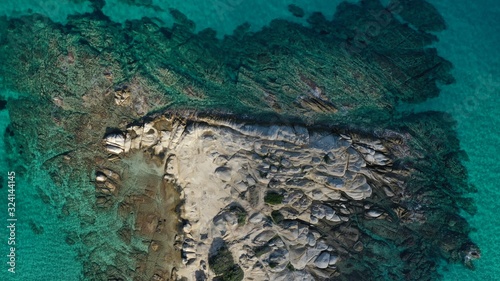 Fototapeta Naklejka Na Ścianę i Meble -  Aerial view of Vourvourou beach, small peninsula in turquoise water of Aegean sea. Waves beating cliff rocky coastline. Halkidiki, Greece.