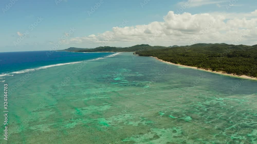 Seascape, coast of the island of Siargao, Philippines. Blue sea with waves and sky with big clouds.
