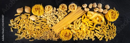 Obraz  z motywem Italian pasta panorama, a flat lay texture of many different pasta kinds, shot from the top on a black background