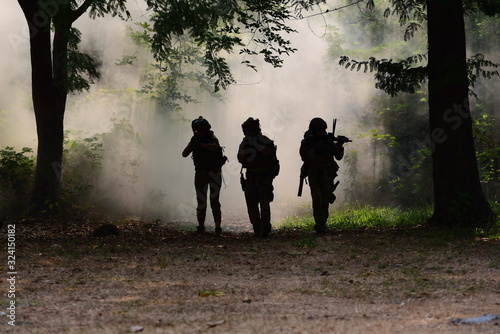 Soldiers with gun or weapon in the silhouette forest area in the smoke of battlefield