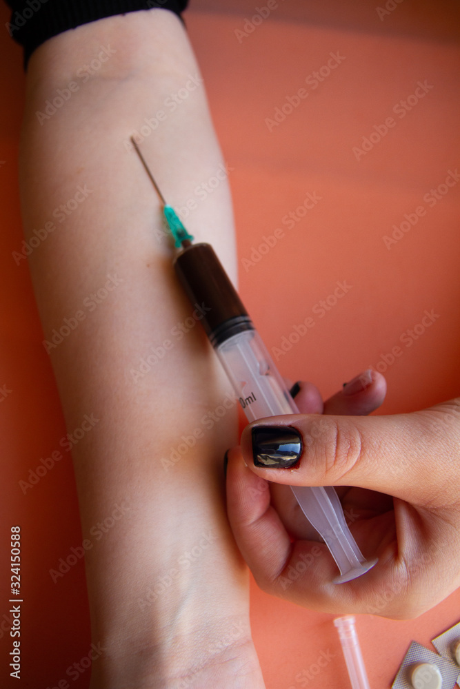 In the hands of a person, a medical syringe with chocolate as a dependency on sugar with a blurred background In the hands of a person, a medical syringe with chocolate as a dependency on sugar with a blurred background