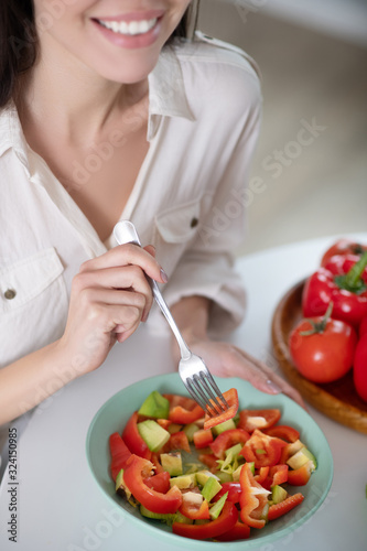 Fresh sliced salad in plate in the hand of young girl.