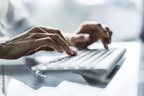 Female hands typing on computer keyboard in sunny office, business and technology concept. Close up