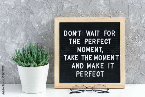 Don't wait for the perfect moment, take the moment and make it perfect. Motivational quote on letter board, succulent flower and glasses on table. Concept inspirational quote of the day
