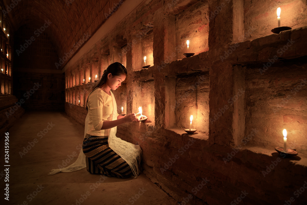 Young Burmese girl prays by candlelight in Bagan, Myanmar
