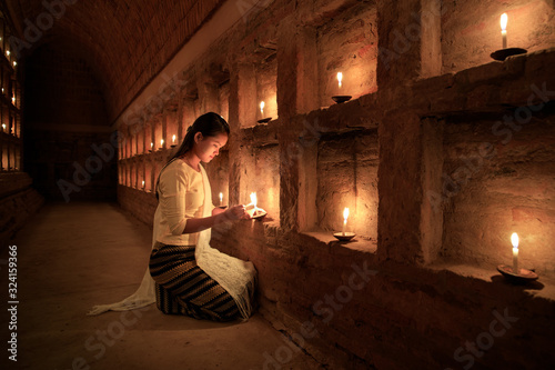 Young Burmese girl prays by candlelight in Bagan, Myanmar