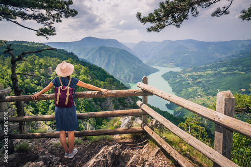 Woman relaxing on mountain cliff looking to view.