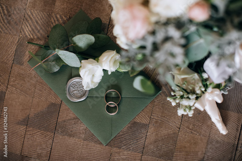 Wedding invitation for guests in green envelope with flowers on wooden background