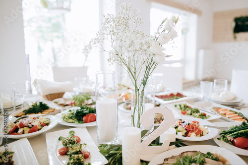 Wedding table decoration in white, food on the tables and flowers bouquets