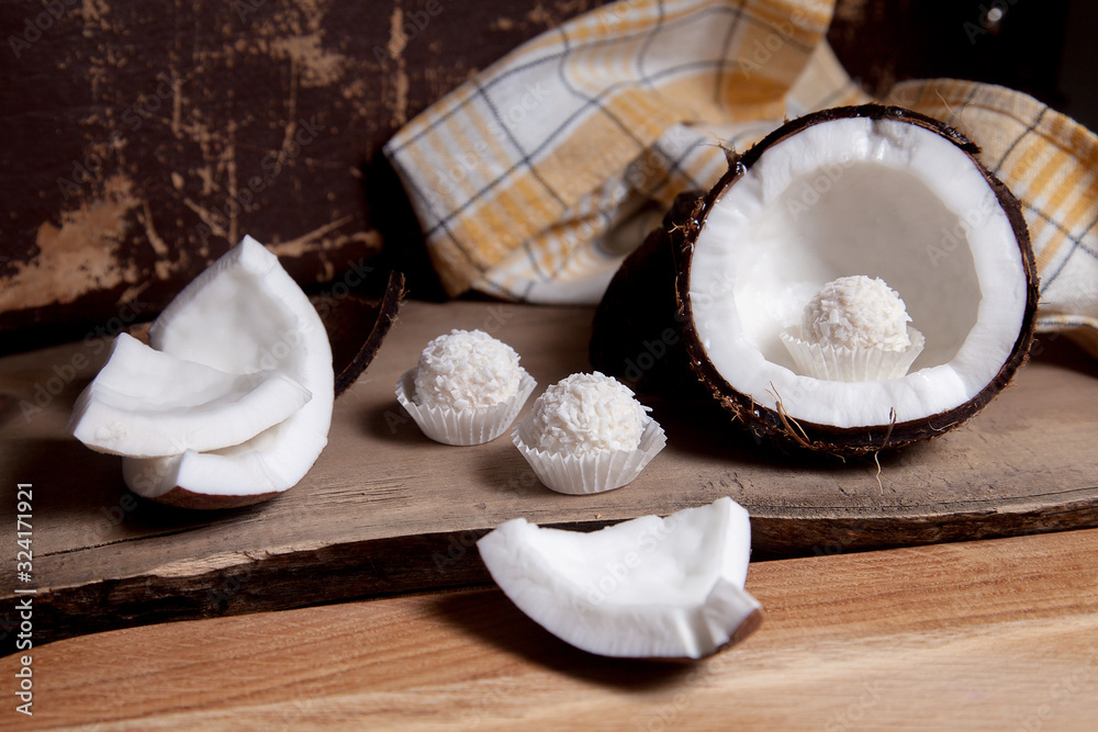 Coconut with white pulp and white candies on wooden background.. Coconut with white pulp and white candies on wooden background..