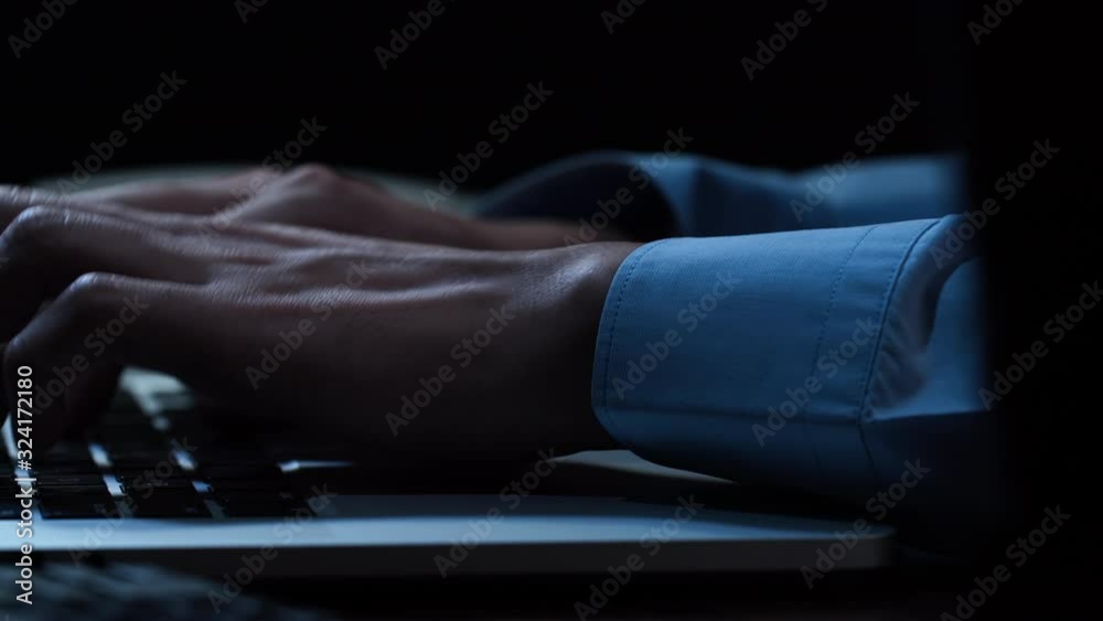 Close up hands of businessman typing on laptop computer keyword at night while working overtime in office Close up hands of businessman typing on laptop computer keyword at night while working overtime in office