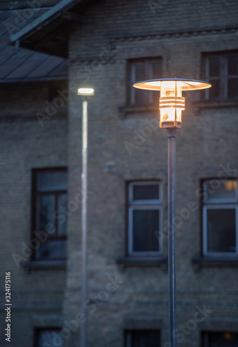 A modern metal lantern illuminates the city in the evening. Close-up.