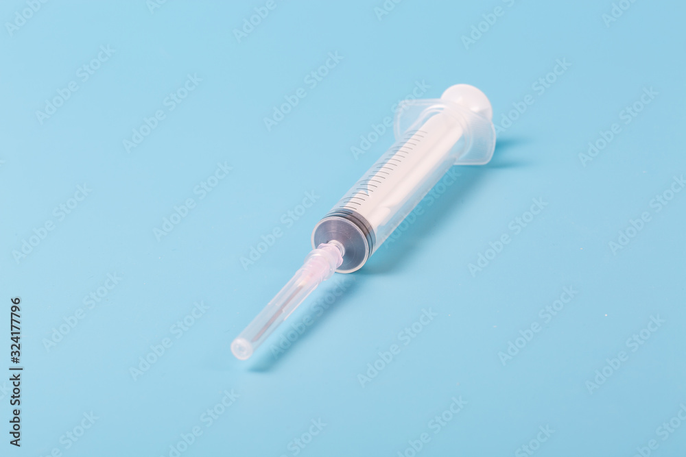 Syringe and miniature human and oral medicine and thermometer macro closeup on blue background Syringe and miniature human and oral medicine and thermometer macro closeup on blue background