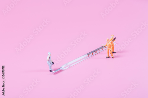 Syringe and miniature human and oral medicine and thermometer macro closeup on pink background