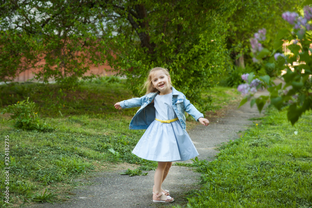 Cute smiling little girl near a bush of blooming lilac Cute smiling little girl near a bush of blooming lilac