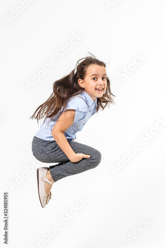 Happy schoolgirl jumping high on white background