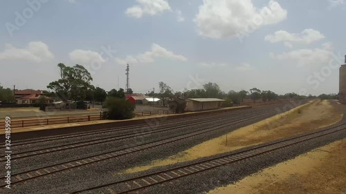 Drone flying backwards along a train track line in a rural country town photo