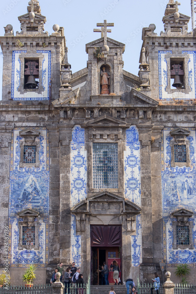 Ildefonso church with tourists in Porto, Portugal. Traditional portuguese exterior with ceramic azulejo tiles. Ancient church in baroque style. Religious architecture.   
