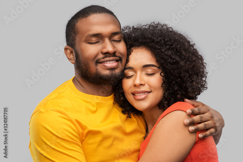 relationships and people concept - happy african american couple hugging over grey background