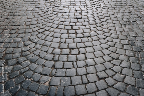The gray paving stones laid out in a semicircle. The texture of the old dark stone. Road surface. Vintage  grunge.