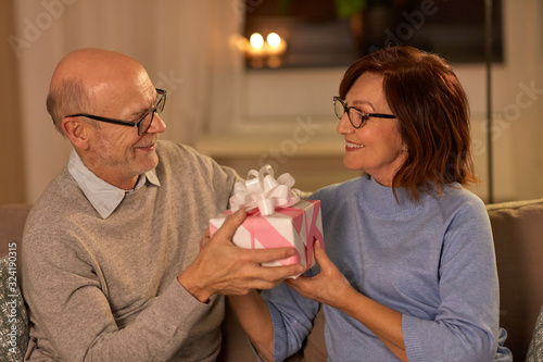 holidays and people concept - happy senior couple with gift box at home