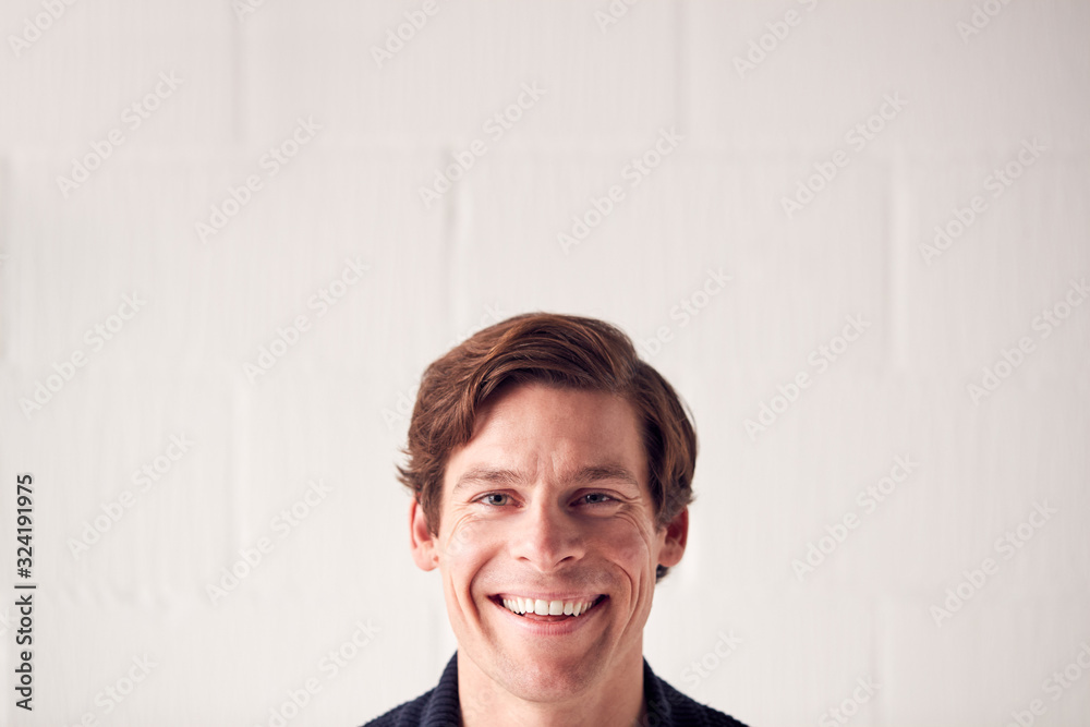 Portrait Of Casually Dressed Smiling Man Standing Against White Studio Wall Portrait Of Casually Dressed Smiling Man Standing Against White Studio Wall