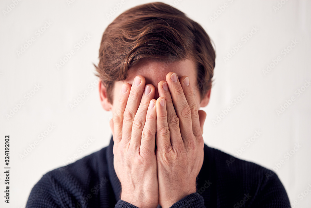 Studio Shot Of Unhappy Man Covering Face With Hands