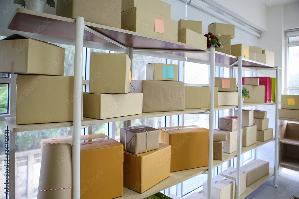 Wrapped cardboard parcel boxes on storage shelf in workplace - Online selling, e-commerce and SME concept Wrapped cardboard parcel boxes on storage shelf in workplace - Online selling, e-commerce and SME concept