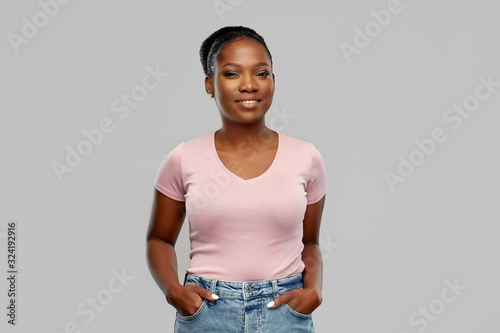 people, ethnicity and portrait concept - happy smiling african american young woman over grey background