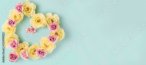 Heart shaped yellow and pink roses on light blue background.  Banner format. Greeting card concept.