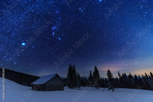 A bright starry night in the mountains with the Milky Way in the sky, Venus and millions of stars highlighting beautiful mountain huts in the valley. © reme80