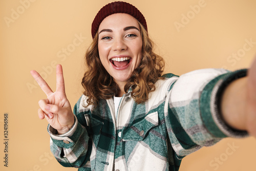 Photo of pretty happy woman taking selfie and gesturing peace signa