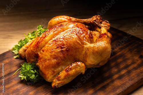 Leinwand Poster Roasted whole chicken on wooden cutting board