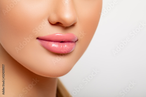 Beautiful Lips Close-up. Makeup. Lip shiny Lipstick. Sexy Lips. Part of Face  Young Woman close up. Perfect plump Lips bodily Lipstick. Peach Color of Lipstick on Large Lips. Perfect Makeup. 