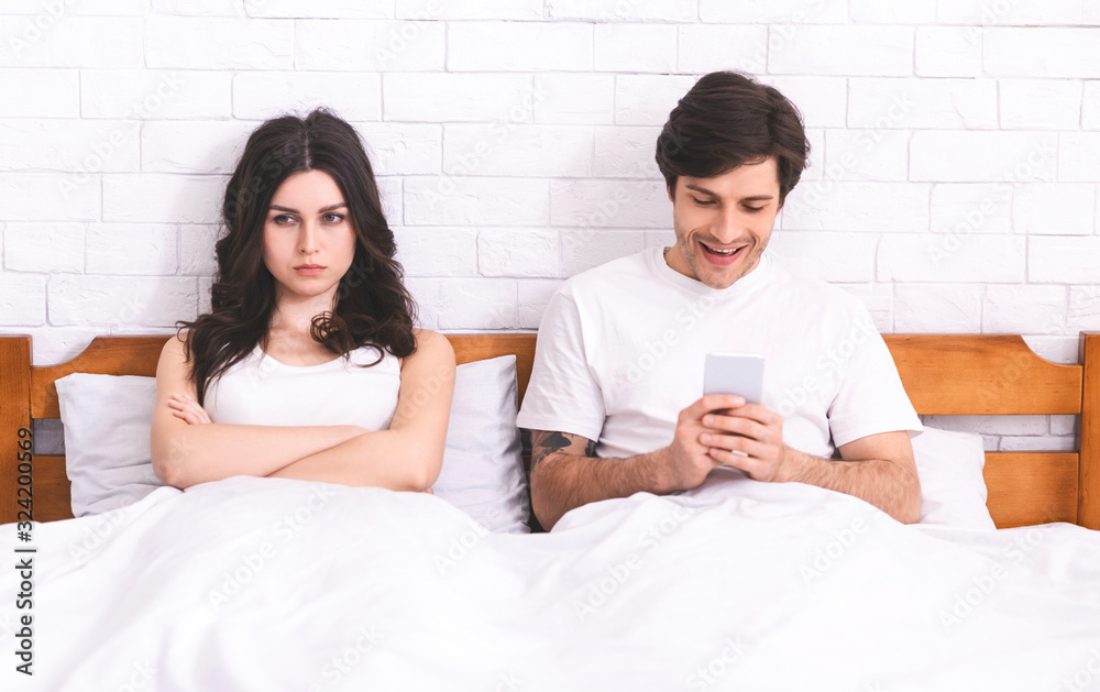 Sad wife ignored by her playing on cellphone husband Sad wife ignored by her playing on cellphone husband