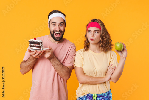 Portrait of athletic young couple choosing beetwen cake and apple