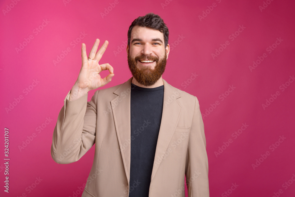 Cheerful bearded man wearing a jacket is showing ok gesture on p Cheerful bearded man wearing a jacket is showing ok gesture on p