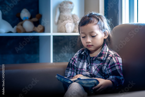 Cute little girl reading the bible on sofa in morning at home. christian concept.